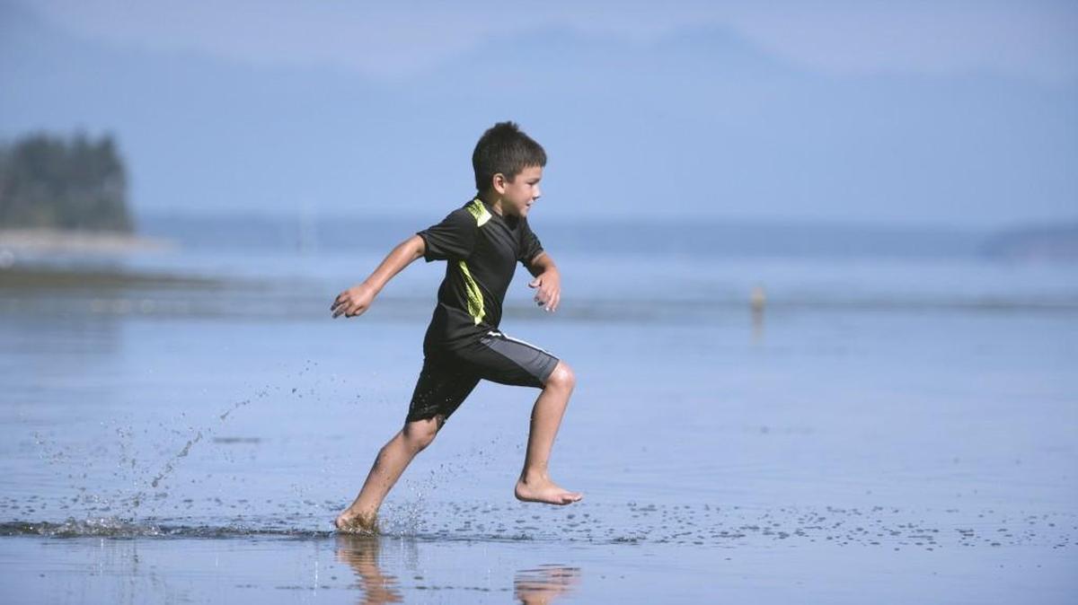 Christopher Butcher of Tenino sprints across the shallow tide flats while playing with family at Tolmie State Park in Lacey in 2016.