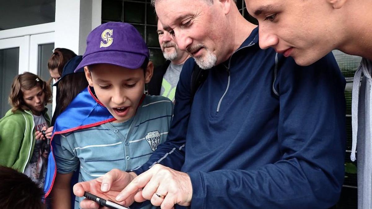 Chuck Valley, vice president for Romanian operations with the Bellingham-based Kidstown International, shows photos to two residents at the Casa Otneil home for abandoned children outside Timisoara, Romania on Sept. 28, 2015.
