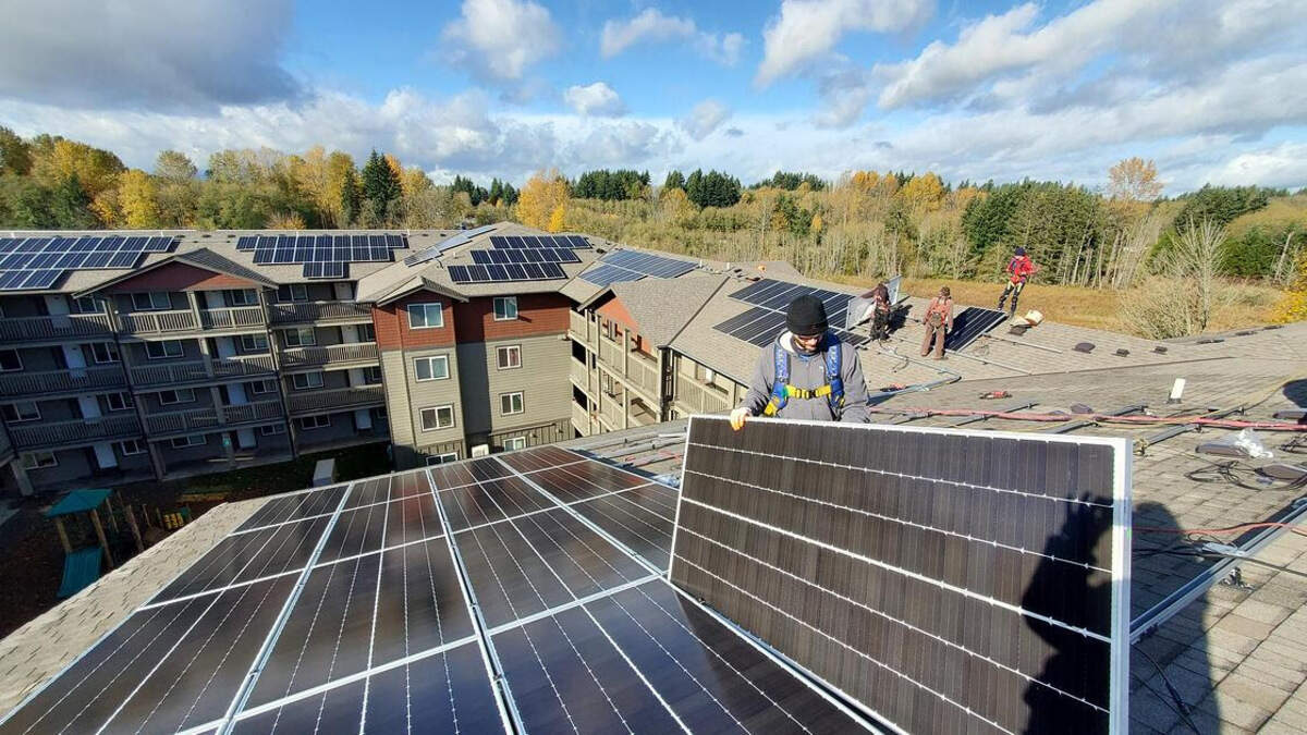 Workers install solar panels on the roof of Merritt Manor, an affordable housing complex on Martin Way in Olympia.