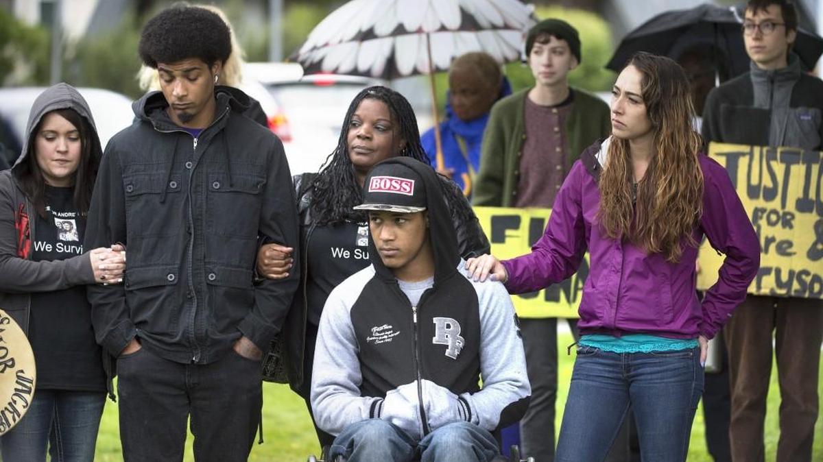 Bryson Chaplin (in wheelchair) and his brother, Andre Thompson (second from left) gather with their mother, Crystal Chaplin (center) and supporters at Woodruff Park in west Olympia before a protest march into downtown Olympia on the anniversary of the police shooting of the two men in Olympia on Saturday, May 21, 2016.