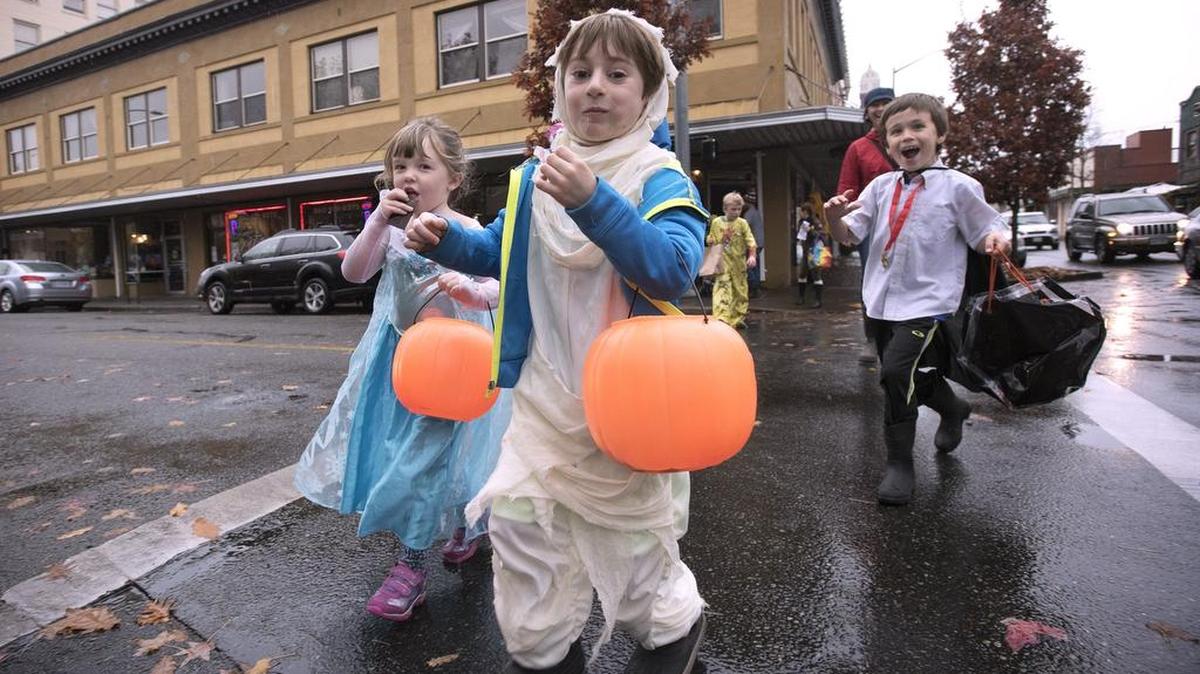 Rhone “Elsa” Rydholm, 4, Luka “Mummy” Jaeger, 6, and Axel “Vampire” Rydholm, 6, snack on candy as they hustle between downtown Olympia businesses during trick-or-treating in 2015.