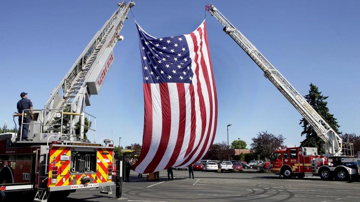 A 40x60 foot American flag is raised by Lacey Fire District 3 and Olympia Fire Department ladder trucks at the start of the Thurston County Veterans Flag Day Ceremony Sunday at the Lacey Civic Plaza. Sponsored by the Thurston County Veterans Council and Thurston County Realtors Association,the American Legion and the Veterans of Foreign Wars organizations the event is held annually on June 14th at the Lacey Civic Plaza. Along with the flag raising the ceremony included guest speakers,Secretary of State Kim Wyman and Diane Pust, president of the Thurston County Realtors Association, and rifle salute by the VFW Post 318 Honor Guard.