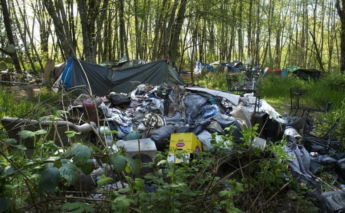 Trash piles up in the homeless camp known as The Jungle on Wednesday. Some of the estimated 100 people living in the wooded area are working to clean up the property to prevent the owners from forcing them out.