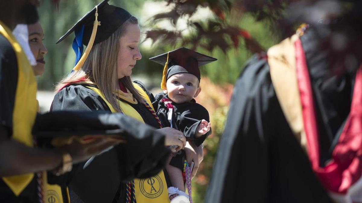 Saint Martin's graduate Tamara Bellisle of Shelton carries her daughter, MaLeah, 5 months, as she waits with fellow bachelor in social work recipients before the 2016 commencement ceremonies at Saint Martin's University in Lacey.