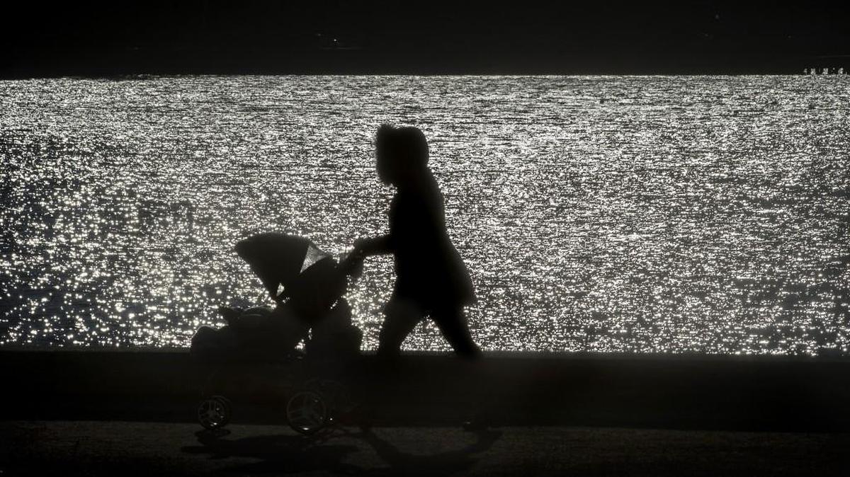 A mother bundled up for the freezing temperatures pushes her stroller around Capitol Lake in downtown Olympia.