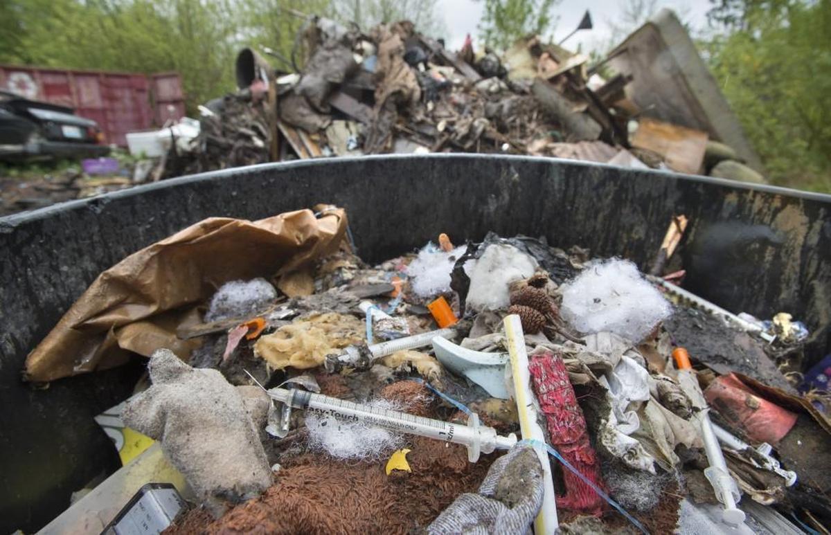 Tons of garbage that includes lived-in school buses, rotting food, buckets of raw sewage, and discarded hypodermic needles litter the property that new owner Angela Ducharme dubbed “Tweaker Town.”