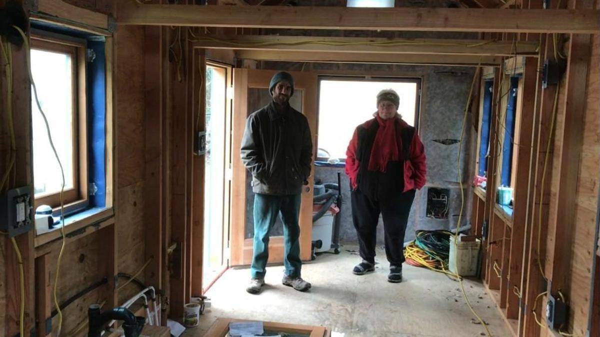 Olympia resident Pat Rasmussen and local contractor Joseph Becker stand inside a tiny house that Becker is building in Thurston County.