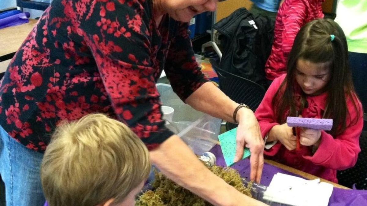 Jeanette Gardner and her grandchildren Ben and Abby make a model of a watershed using a paint tray, soil, sponges, moss and clay during a class at the LOTT WET Science Center in Olympia.