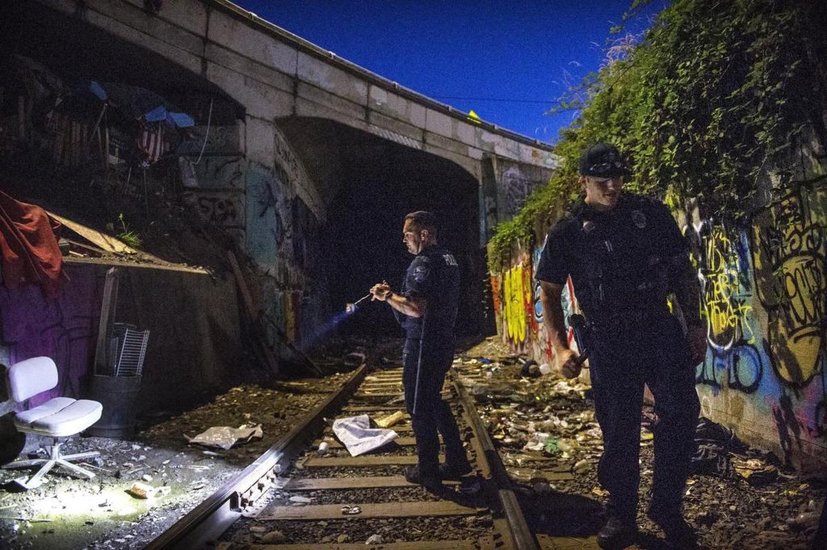 Olympia police officers Jacob Theis, left, and Jordan Reisher check out the area around the train tunnel that runsthrough downtown during a nighttime patrol this month.