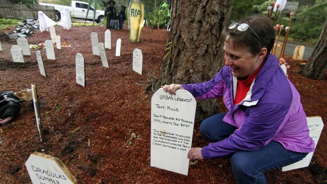 Tracy Perkins adjusts one of the many creative tombstones in her front yard in preparation for the coming Halloween night fun.