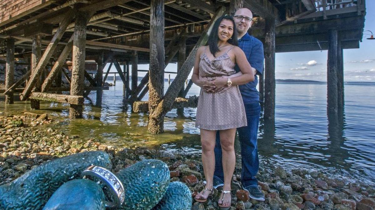 
Chris and Minnette Sills stand on the beach under Katie Downs restaurant on Tacoma's waterfront Thursday. After their wedding, she accidentally dropped her new ring (held in the foreground in this photo) from the restaurant's deck. It was later found with the help of experts using metal detectors.
