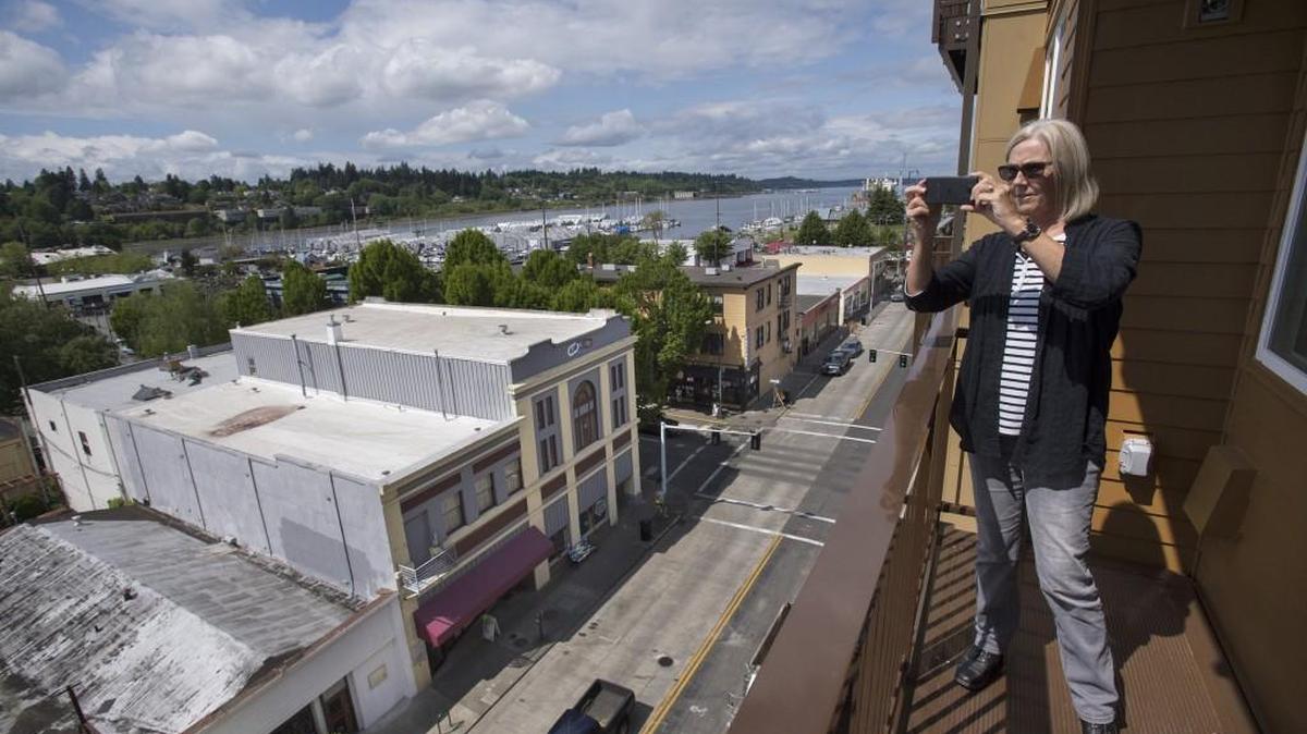 Jackie Backhaus of Honaunau, Hawaii, takes photos from the sixth-floor balcony of a one-bedroom apartment as she tours the 123 4th Apartments in downtown Olympia on Friday, April 29, 2016.