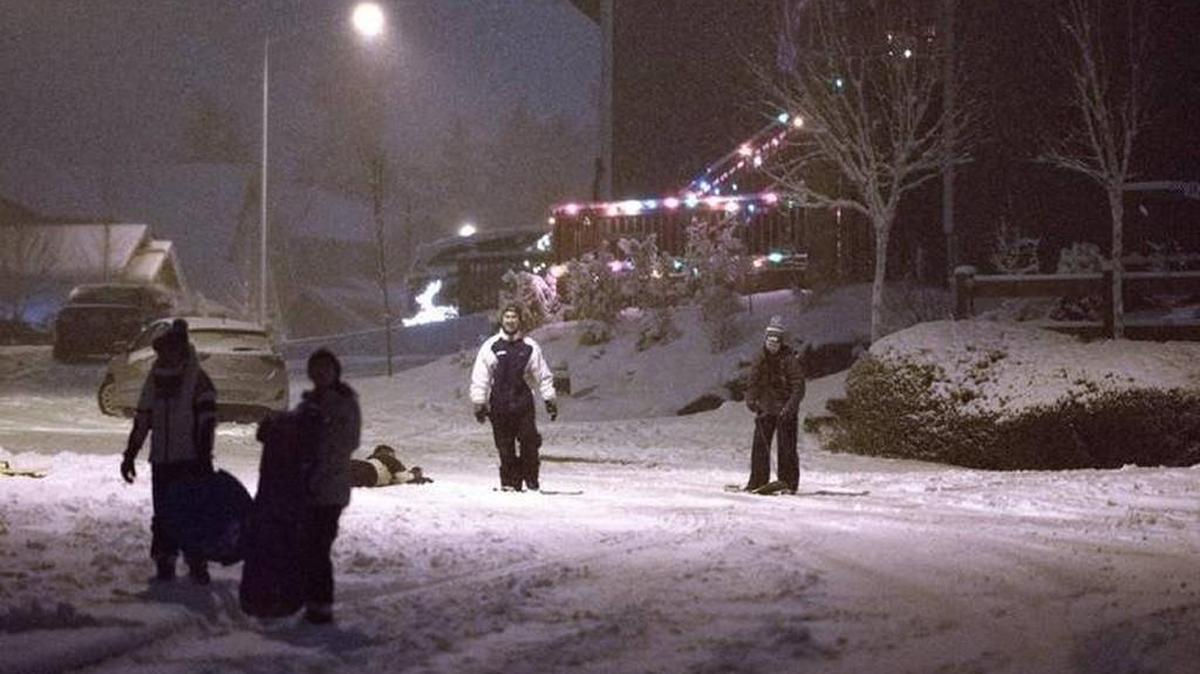 Staff file: Residents take in the snowy streets on Tumwater Hill on Thursday night, Dec. 8, 2016. Many school districts are closed or delayed today due to the snowy weather and slick roads.