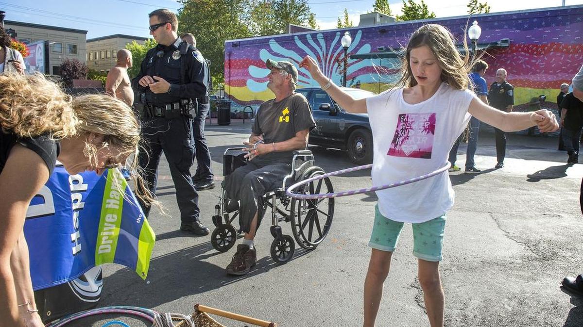 
From left, Anne Larsen sets up an information booth on distracted driving as Olympia police officer Paul Frailey and Marty Linzy talk and Megan Larsen tries out a hula hoop Tuesday during the National Night Out Against Crime gathering at the Artesian Commons Park in downtown Olympia.
