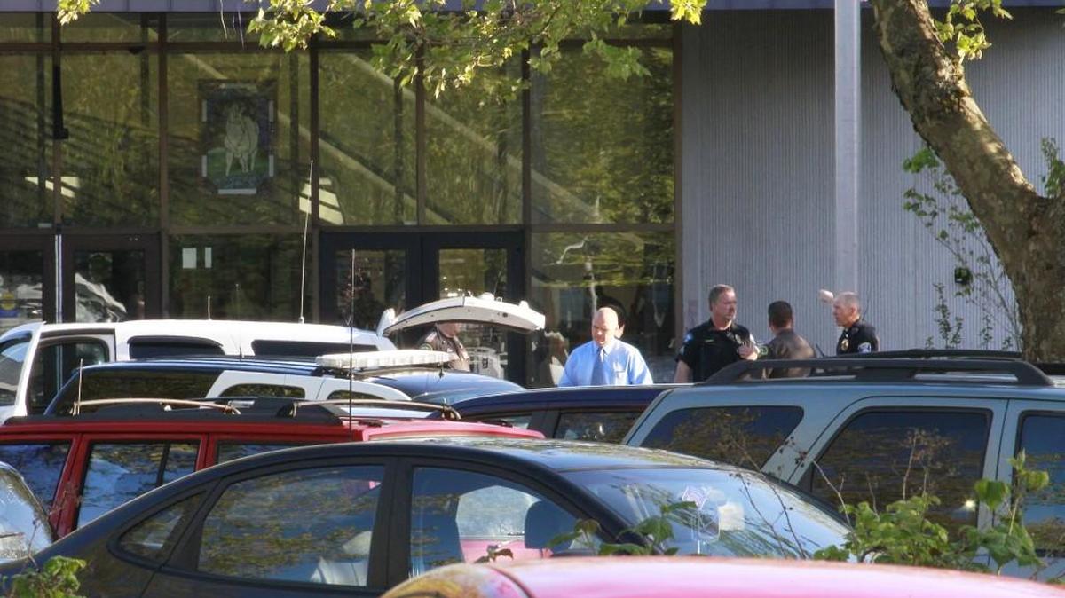 
School staff and law enforcement members stand at the main entrance at North Thurston High School on April 27 after two gunshots were fired inside. The 17-year-old suspect will be tried in Thurston County Juvenile Court.
