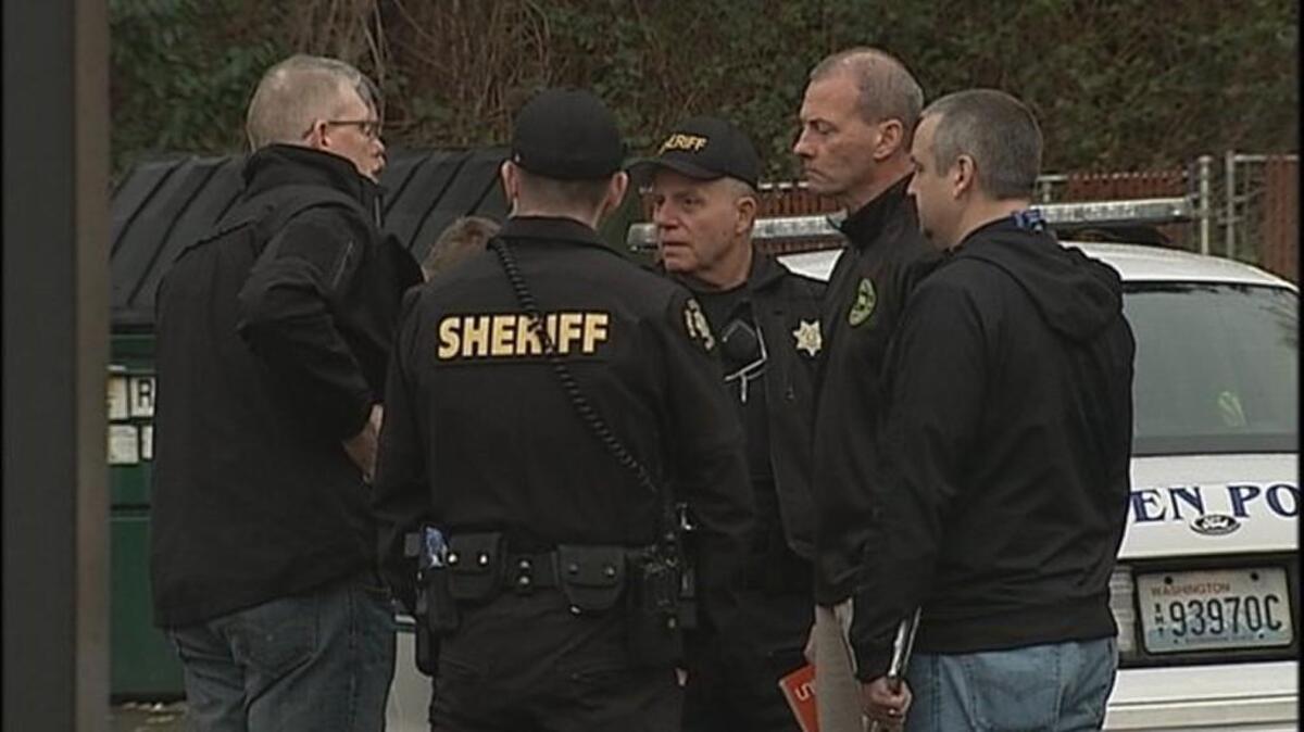 Investigators work a crime scene at a convenience store in the Boulevard Park area of South King County early Sunday. A masked man wielding a hatchet walked into the store swinging before he was fatally shot by a customer.