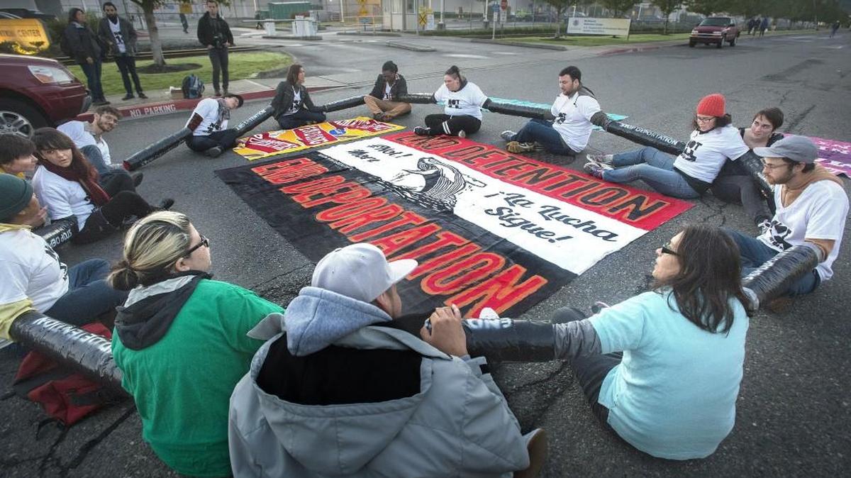 Protesters from Not 1 More and Northwest Detention Center Resistance block the road on East J Street to Northwest Detention Center on Monday in Tacoma . The protesters, part of a coalition, hoped to to stop deportations at the Northwest Detention Center on the Tideflats.
