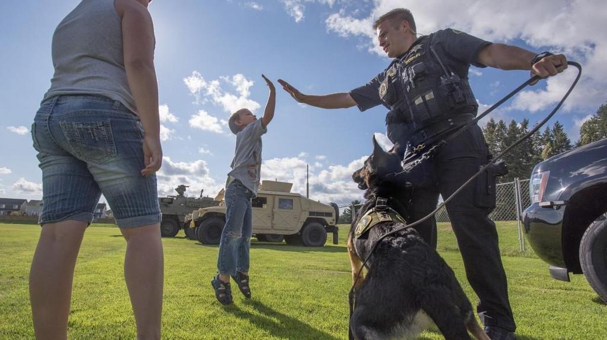 Anthony Komenski, 4, gets a “thank you” high five from Thurston County Sheriff’s deputy Chris Packard after helping walk K-9 officer “Dexter” during the National Night Out celebration at Horizon Pointe Park on Tuesday.