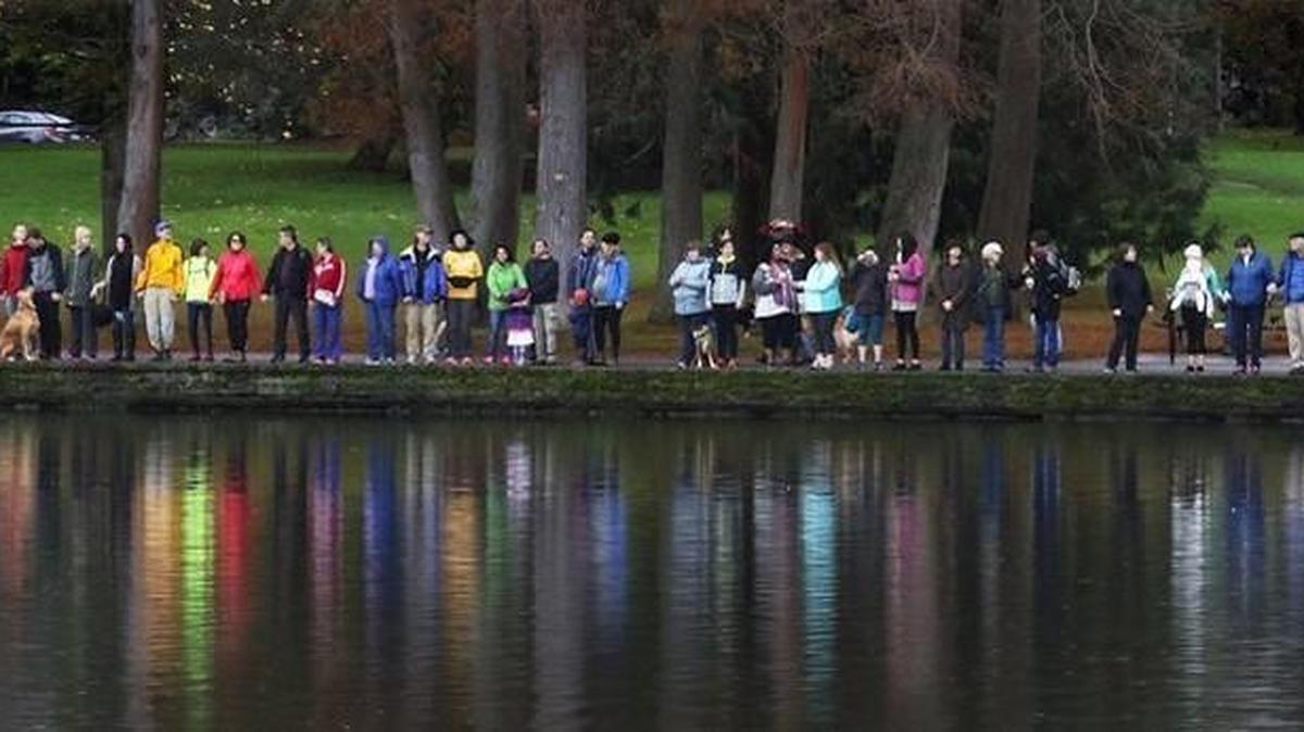 Rain gear is reflected in Green Lake on Saturday as thousands turned out in an attempt to form a circle all the way around the lake.