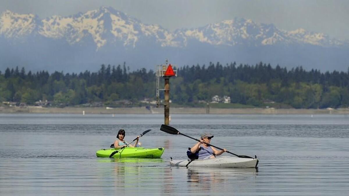 Enjoying a summer like April afternoon with the majestic Olympic range as a backdrop kayakers Bonnie Whitaker (left) and Kelly Millett glide into the Swantown Marina docks as stellar and even hot temperatures for this time of year are forecasted around the region.