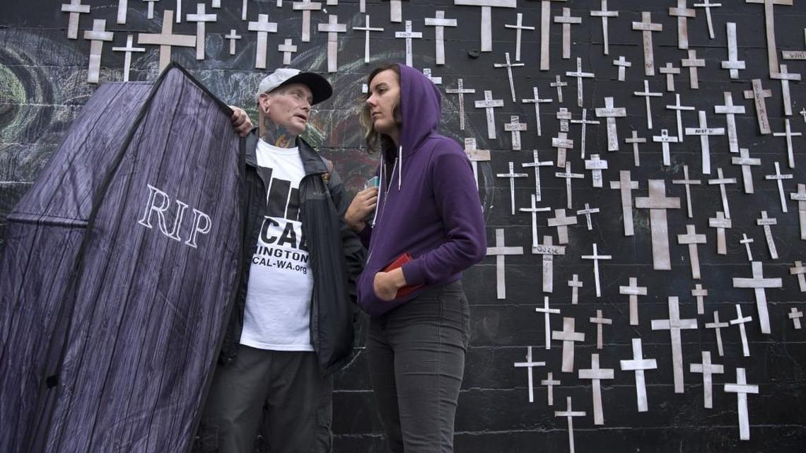 Jeffrey Packowski and Meg Martin stand alongside the wall of remembrance during the National Overdose Awareness Day event at the Artesian Commons in downtown Olympia on Wednesday.