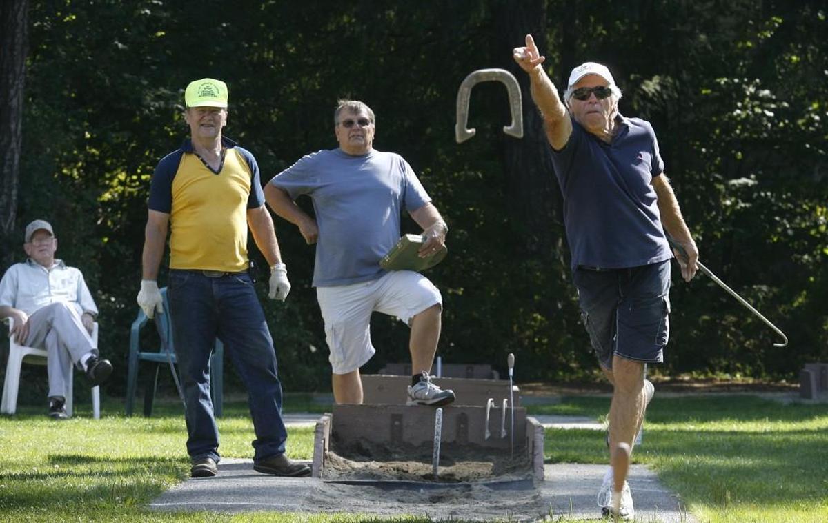 File photo: Stan Speers (left), a former horseshoe state champion from Toledo, watches as opponent Sam Darnell of Boston Harbor tosses a horseshoe at the Olympia Horseshoe Pitching Club in 2012.