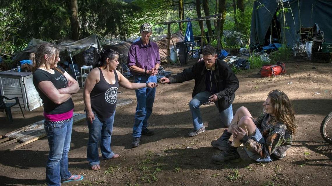 From left: Jaclyn Reade, Anne Brown, Jimmy Nixon, Tim Beavers and Brandy Wayne Campbell gather outside their tents and cabins in the homeless camp in Olympia referred to by residents as The Jungle on Wednesday. Reade estimates about 100 people are living in the wooded area between Martin Way East and Pacific Avenue Southeast.