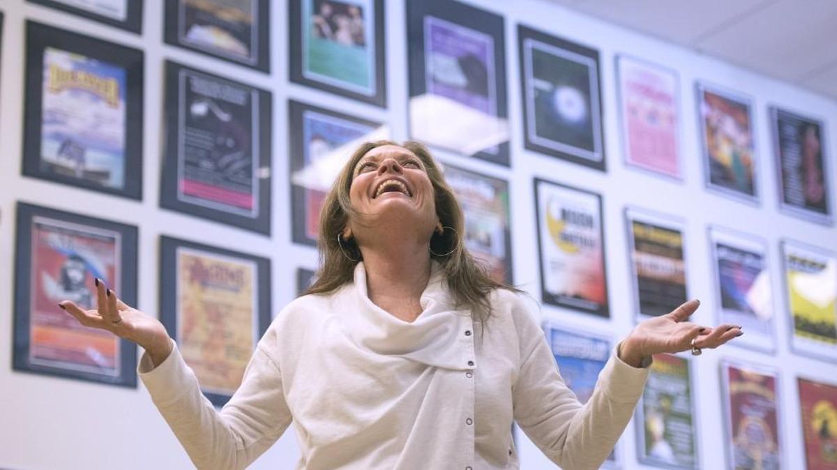 The walls of the Timberline High School theater entryway are covered with posters from the dozens of productions Brenda Amburgy has directed. She is shown before dress rehearsal for “Young Frankenstein,” her final production at the school. She is retiring.