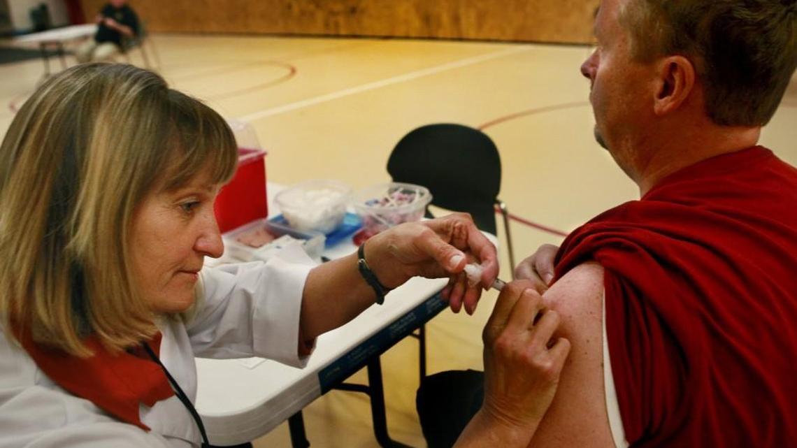 Capital High School teacher Troy Mickelson is one of the first to get his flu shot by Linda Davelaar of the Seattle Visiting Nurse Association during a Monday clinic offered by that organization and open to all Olympia School District students and employees. The district is offering two more clinics later this month. Staff file, 2014