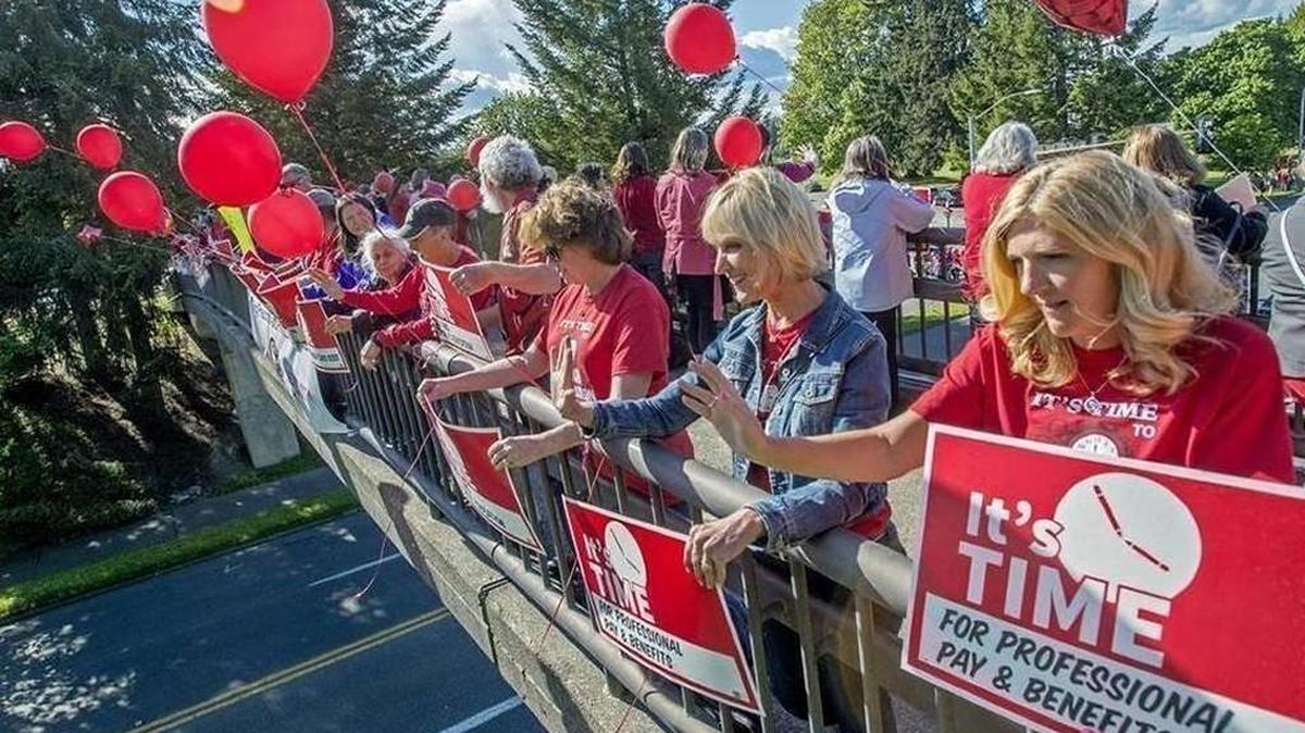 Dozens dressed in red wave signs in support of better funding for education from the pedestrian bridge over Capitol Way on May 6 during a rally organized by the North Thurston Education Association. The union’s members voted to walk off the job during time designated for teacher training and professional development activities, as part of what was referred to as a statewide “rolling walkout” to protest education proposals that were in front of the Legislature last spring. NTEA members and the district recently approved a 2-year contract.