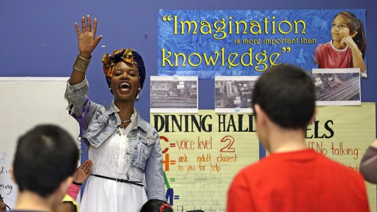 Instructional assistant Catrice Dennis leads students last week in a morning ritual and song to begin the day at First Place Scholars school in Seattle. The tuition-free private elementary in the city’s Central District neighborhood serves low-income students, many of them homeless or at risk of becoming homeless.
