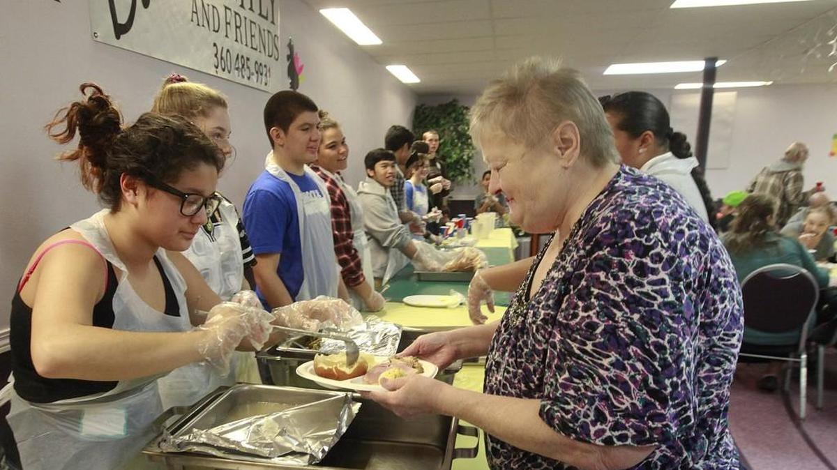 Volunteer Haliya Charley fills Terry Thomas’ plate during Barb’s Family and Friends Thanksgiving meal at The United Churches, downtown Olympia.