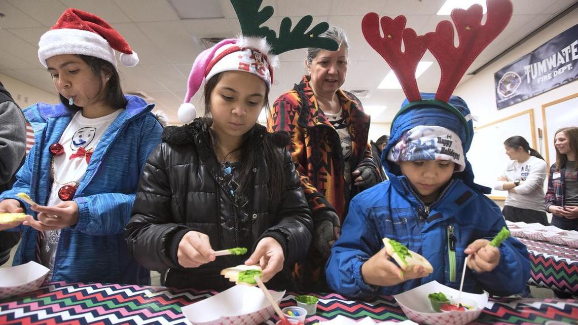 Mia Rebey (from left), 11, Carmen Rebey, 9, and Kamran Rebey, 7, decorate cookies at the 2016 Tumwater Christmas Tree Lighting Festival with their grandmother, Anna Wilson of Littlerock, at the Tumwater Fire Department.