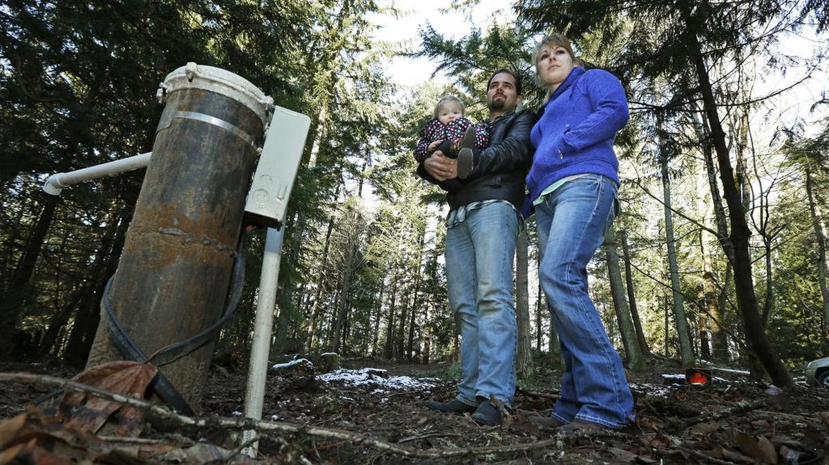Bud Breakey and his wife, Deborah, pose with their daughter Kaylin, 15 months, by the water well they paid to drill on property they own near Bellingham where they hope to eventually build a house. Several bills currently being proposed by lawmakers are taking aim at a recent Washington Supreme Court decision that put the onus on counties to determine whether water is legally available in certain rural areas before they issue building permits.