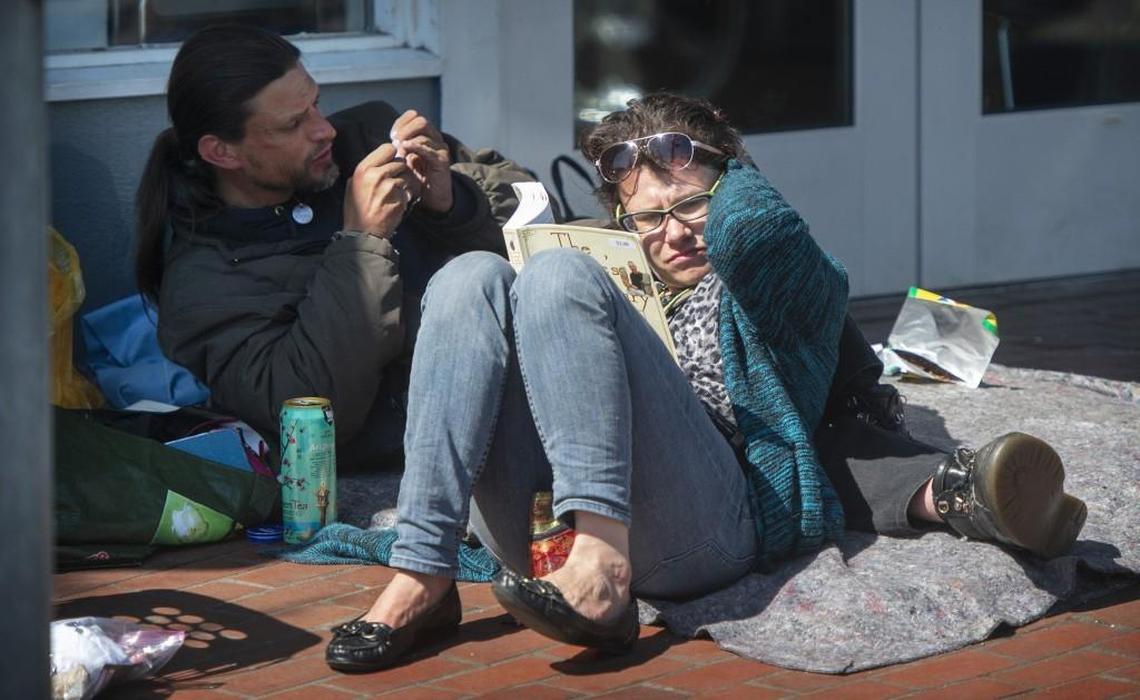 A couple relaxes outside the Providence Community Care Center in downtown Olympia on Wednesday. The center is filled each day with homeless people looking for a shower, laundry, medical care, social services or just a place to rest.