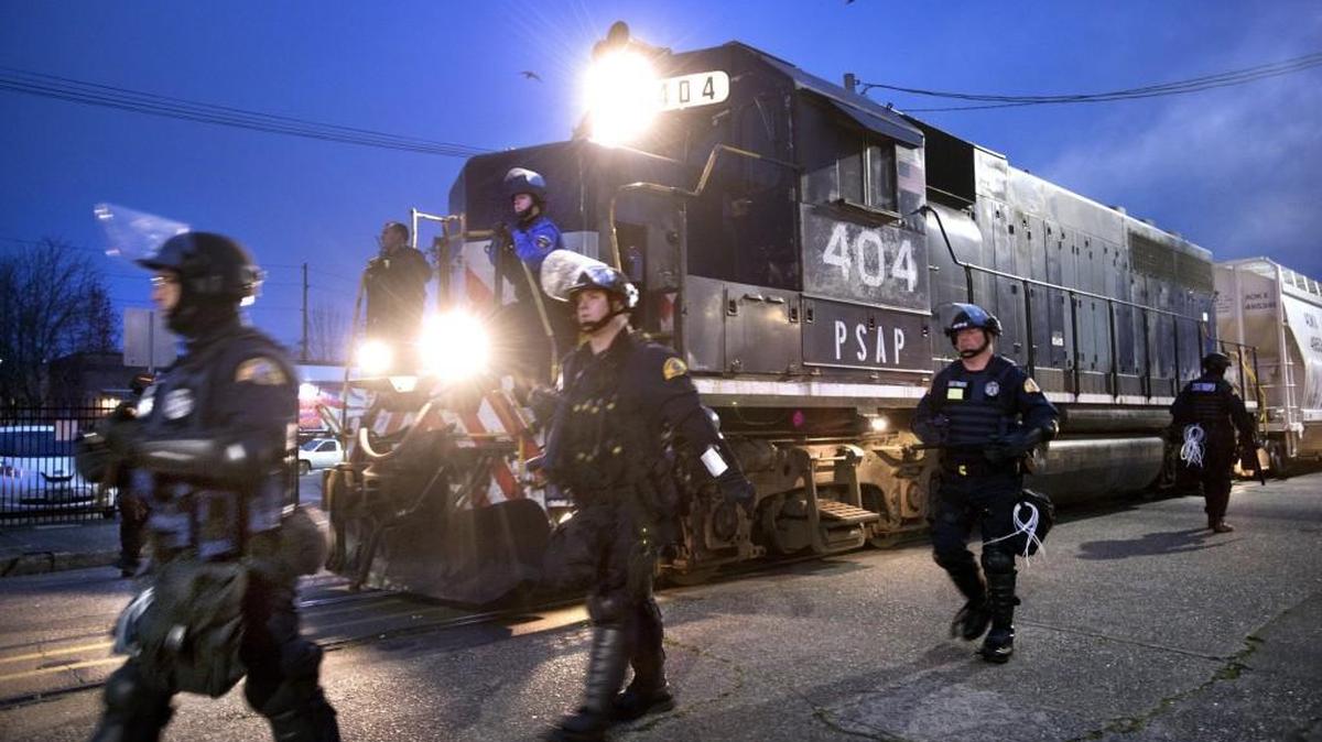 Law enforcement officers escort a train carrying ceramic proppant materials as it moves from the Port of Olympia through downtown early on Friday, Nov. 17.