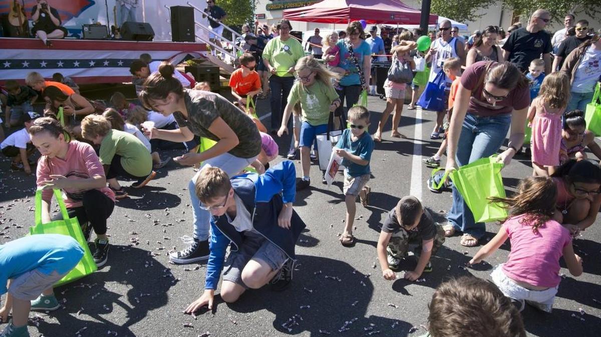 
Kids scramble for thousands of Tootsie Roll candies falling from a helicopter overhead during the Hawks Prairie Rotary’s 13th annual Military Family Day in the parking lot at Cabela’s in Lacey on Sept. 12, 2015. The all-free activities included a ceremony to honor families from each branch of the military, bounce houses, live music, food and drinks.
