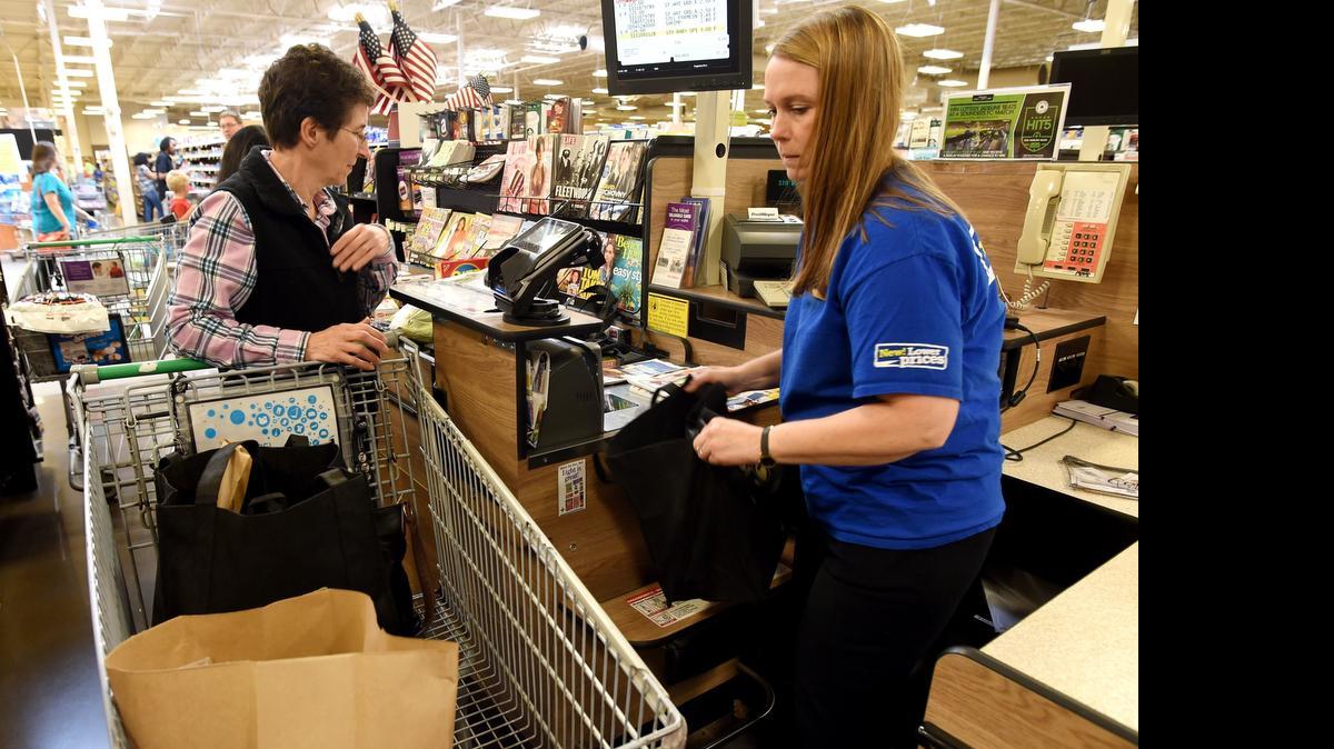 
Lacey Fred Meyer cashier Kim Williams loads customer Becky Russell's cart during a visit May 18. A group has asked the Lacey City Council to allow it to pay for the cost of putting the city’s plastic bag ban on the ballot.
