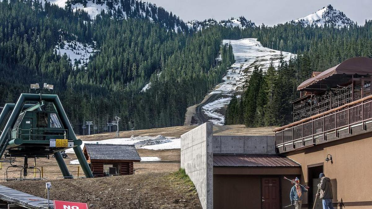 A solitary skier walks by maintenance worker Thomas Wieman as he cleana up at Crystal Mountain in 2014. A warm winter that year translated into one of the worst ski seasons in Western Washington’s history, record low snowpacks and worries of summer water shortages.