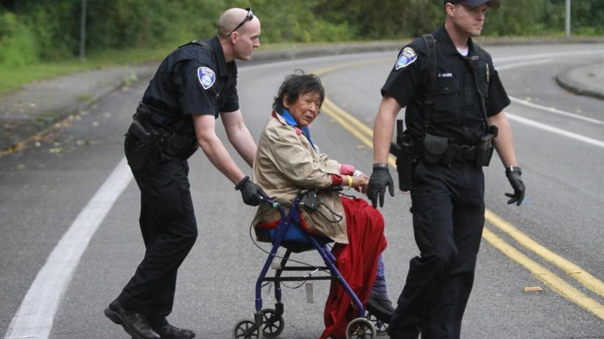 
Olympia police Officer George Clark, left, helps a homeless woman known as Dee Dee cross a street to a police car for a ride in September 2014. The woman had earlier requested an ambulance to a hospital, but refused treatment when she arrived. Clark said Dee Dee was uncharacteristically friendly in this encounter with police. “There comes a point where you keep offering to help people, and they just give you the finger, that you feel like giving up. We can’t force people to get help,” Clark said. Assisting at right is officer Jon Hazen.
