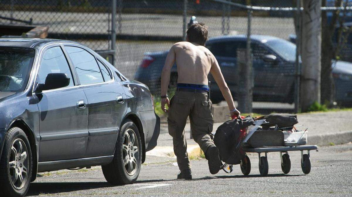 A man moves his belongings through the street in downtown Olympia in May.