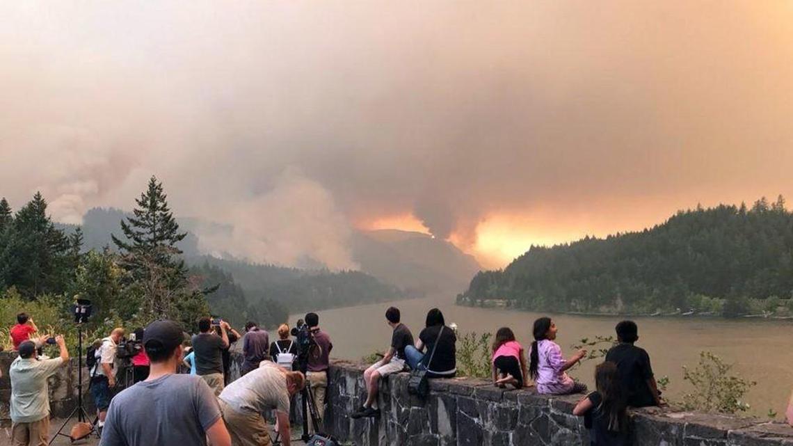 This photo provided Monday by Inciweb shows people at a viewpoint overlooking the Columbia River watching the Eagle Creek wildfire burning in the Columbia River Gorge east of Portland. A stretch of Interstate 84 remained closed Tuesday.