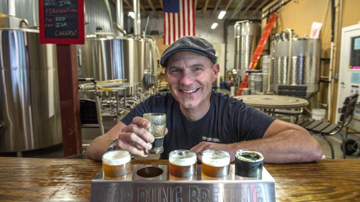 Firefighter and brewery operations manager Casey Sobel of Top Rung Brewing Company of Lacey enjoys a sampling of his craft beers in July. Sobel says the brewery is expanding production and adding equipment to meet demand.