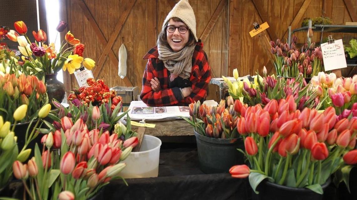 Zowie Aleshire of Independence Valley Farm in Rochester, is surrounded by colorful tulips during the opening day of the Olympia Farmers Market on Thursday, April 2, 2015.