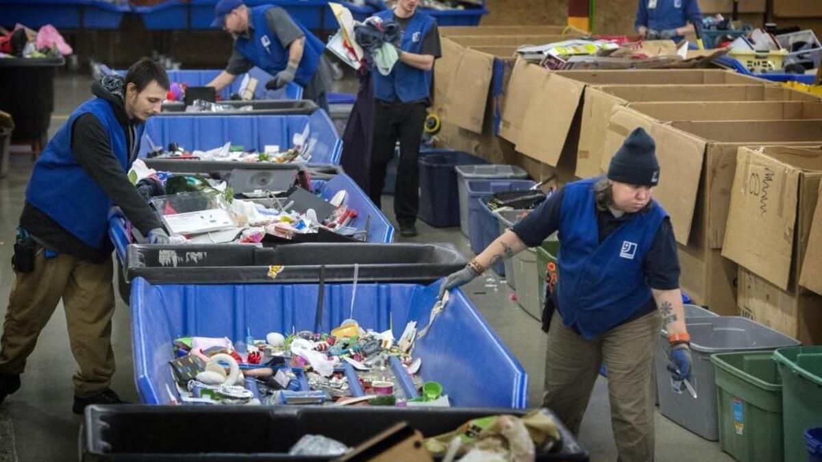 Goodwill production workers Sean Alsup, left, and Terry Seelig, right, move items for recycling after the items were not sold at the Goodwill Outlet in Olympia.