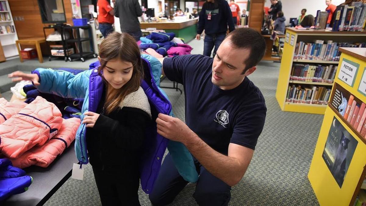 Tumwater firefighter/paramedic Matt Somnis helps second-grader Hailee Keith try on one of more than 300 donated children’s coats Thursday, Nov 19, as part of the Tumwater Firefighter’s Local 2409 “Operation Warm” coat give-away at Michael T. Simmons Elementary School.