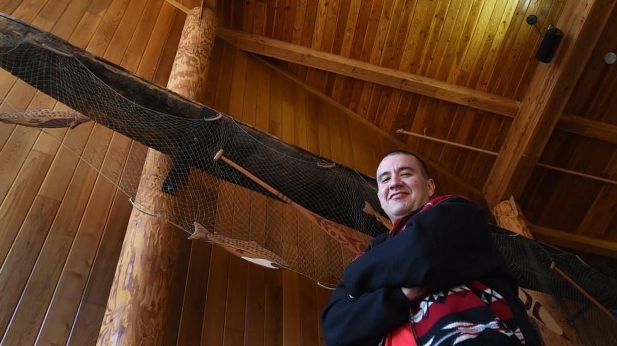 Nisqually tribal member Willie Frank Jr. III stands below the elevated canoe used by his father, Billy Frank Jr. The canoe is on display at the Wa He Lut Indian School in Nisqually.