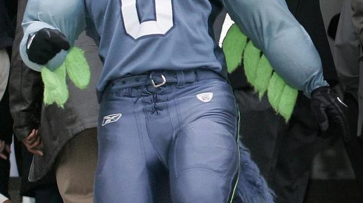 Seattle Seahawks football players Kelly Herndon, background right, and Jordan Babineaux, second from right foreground, wave as they stand near "Blitz," left, the Seahawks' mascot and film the crowd Sunday, Jan. 29, 2006, at a football rally in Seattle. Blitz will be in Olympia Dec. 2.
