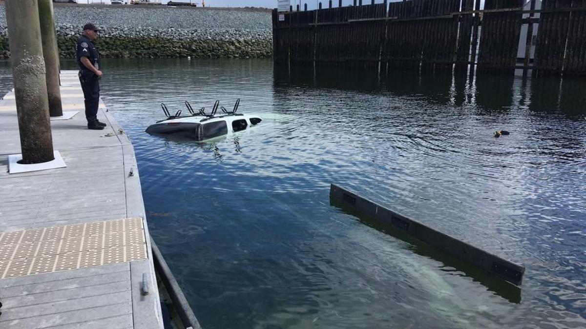 A Pierce County sheriff’s deputy looks over an SUV that went into Commencement Bay in Tacoma on Friday morning as divers work to get it ready for removal from the water.