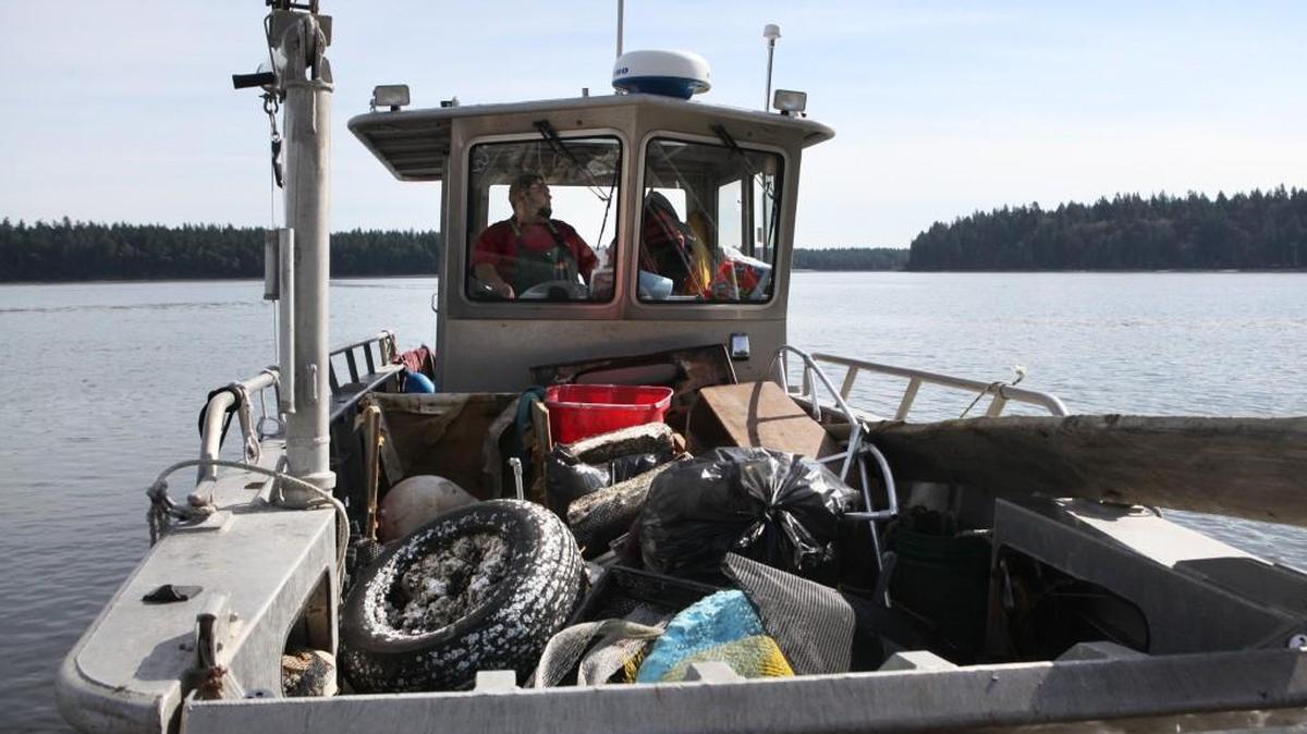FILE PHOTO: Daniel Kuntz brings in a boat load of garbage to Arcadia Point west of Shelton during a Squaxin Island beach clean-up in 2012.
